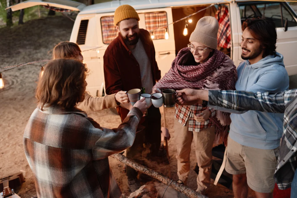 Group of friends toasting with mugs around a campfire under stars